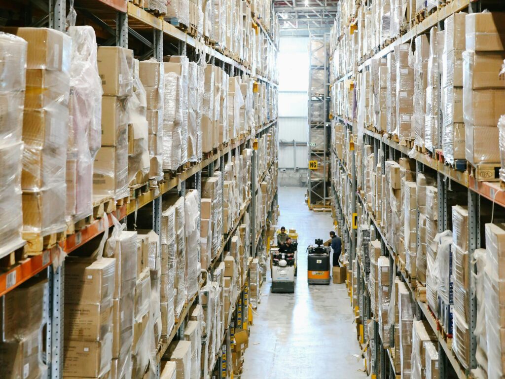 pexels-photo-5156696-5156696 Spacious warehouse aisles lined with shelves stacked with boxes and packaging.